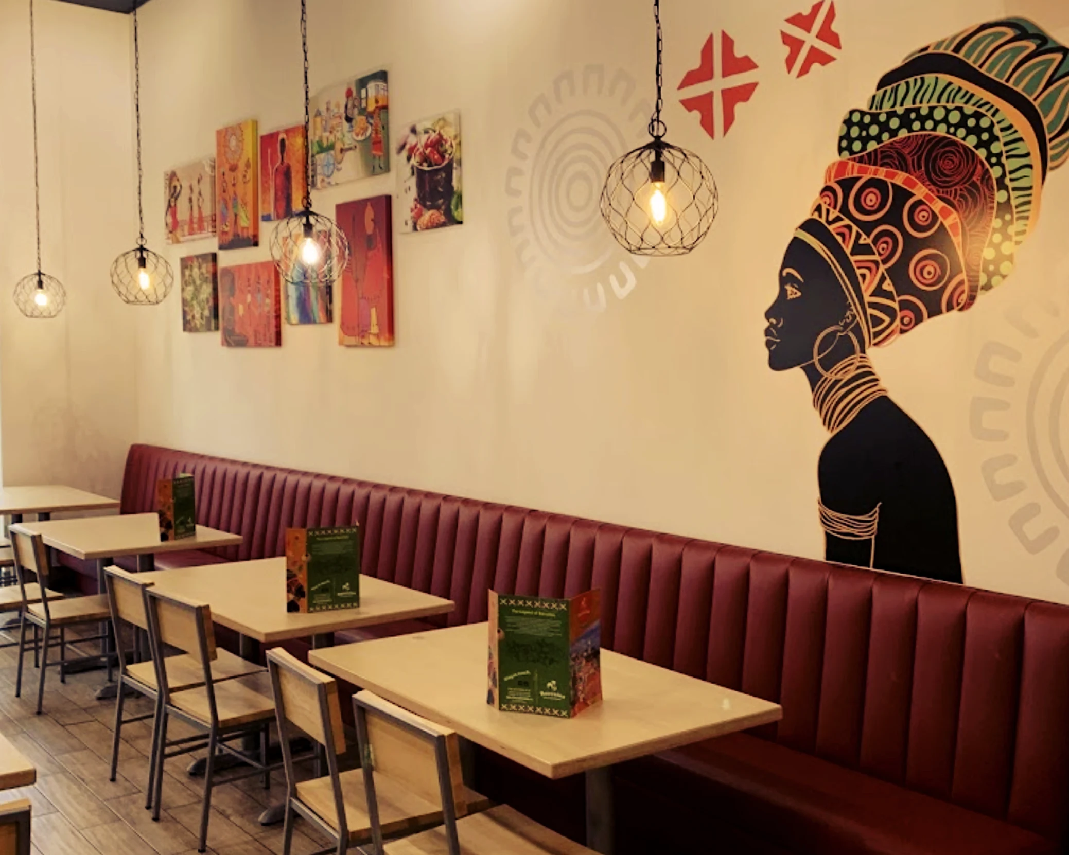 A view of an interior dining area, including custom vinyl bences, vibrant wall art, and atmospheric pendant lighting.