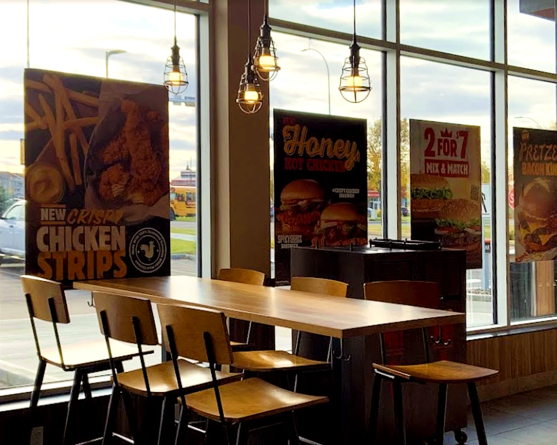 The interior of a Burger King, including wooden seating, a lighting feature, wainscotting, and slate flooring.