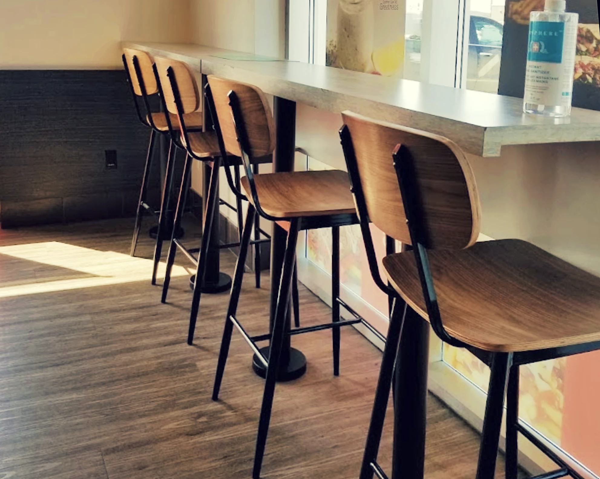 Bar chairs in the late afternoon light, neatly lined up against a dining area inside a mediterranean restaurant.